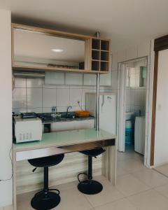 a kitchen with a counter with a sink and two stools at Studio Iracema in Fortaleza