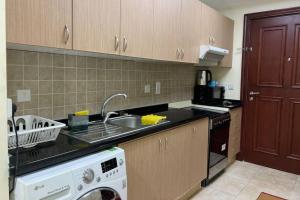 a kitchen with a sink and a washing machine at Cozy 1 Bed in Sports City in Dubai
