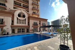 a large swimming pool in front of a building at Cozy 1 Bed in Sports City in Dubai