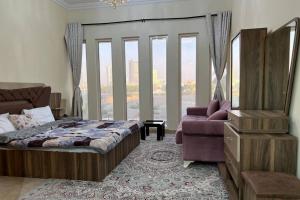 a bedroom with a bed and a couch and windows at Cozy 1 Bed in Sports City in Dubai