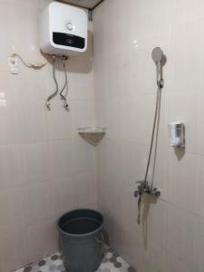 a bathroom with a bucket in the corner of a shower at Asmanida Syariah Guest House in Bukittinggi