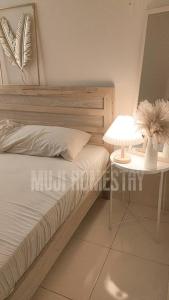 1 dormitorio con 1 cama y 1 mesa con lámpara en Muji Homestay, en Sungai Pelik