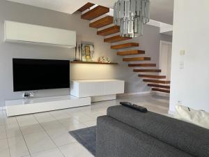 a living room with a tv and a staircase at "Ferienhaus am Mondsee" mit direktem Schafbergblick im Salzkammergut bei Salzburg in Mondsee