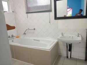 Rato Thato Guest House في ديربان: حمام مع حوض ومغسلة ومرآة