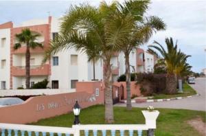 a white fence with palm trees in front of a building at Apartment in Mohamadaya Morocco in Mohammedia