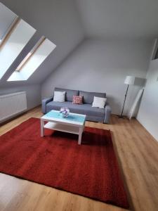 a living room with a couch and a red rug at Bohém Apartman in Nyergesújfalu