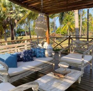 a wooden porch with two chairs and a chandelier at Villa Baleia 