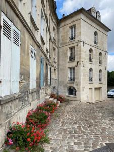 a stone building with flowers in front of it at Le logis de l'Epte in Saint-Clair-sur-Epte