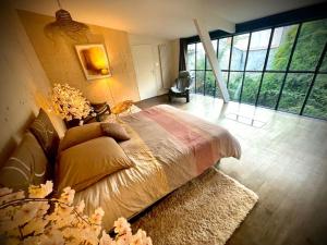 1 dormitorio con 1 cama en una habitación con ventanas grandes en La Dame de Verre en Rochefort