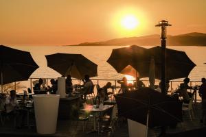 a group of people sitting at tables with umbrellas at Hôtel Propriano Arena Bianca in Propriano