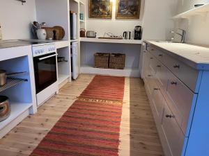 uma cozinha com armários brancos e um tapete no chão em Farmens Gæstehus em Svebølle