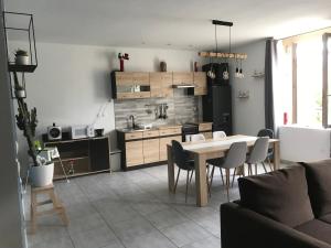 uma cozinha e sala de estar com mesa e cadeiras em Appartement confortable centre du village em Pélussin