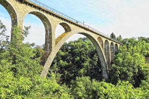 uma ponte com um comboio em cima dela em Appartement confortable centre du village em Pélussin