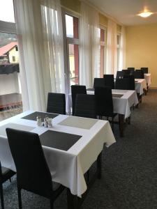 a row of tables with black chairs and white table cloths at Penzion Kycera in Oščadnica