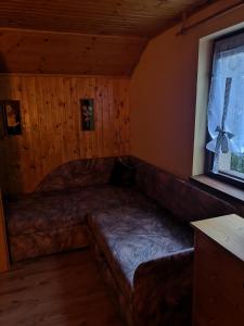 eine Couch in der Ecke eines Zimmers mit Fenster in der Unterkunft M&M Chata Kokava Línia in Å oltÃ½ska