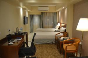 ミニヤーにあるOmar El Khayam Al Minya Hotelのベッド、デスク、椅子が備わるホテルルームです。