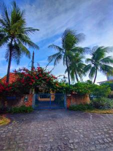 a gate to a house with palm trees and flowers at HOSTEL Recanto do Cajueiro in Maceió