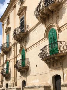 a building with green windows and balconies on it at Room 55 in Noto