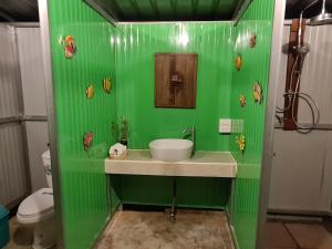 baño verde con lavabo y aseo en Villa Noina Glamping, en Ban Nong Takhain
