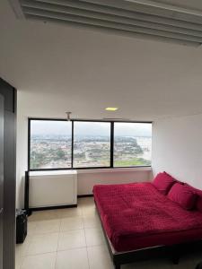 1 dormitorio con cama roja y ventana grande en Departamento en la mejor zona de Guayaquil, en Guayaquil