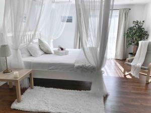 1 dormitorio con 1 cama con cortinas blancas y alfombra en Romantic Studio Cottage en Lambton Shores