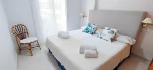 a white bed in a small room with a chair at Apartamento Dianium by DENIA COSTA in Denia