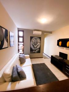 a living room with a white couch and a tv at Apartamentos Orrit Real Estate in Pipa