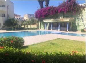 a swimming pool with a building with purple flowers at Apartment in Mohamadaya Morocco in Mohammedia