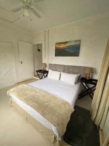 a bedroom with a large white bed with two tables at Mon Desir in Pietermaritzburg
