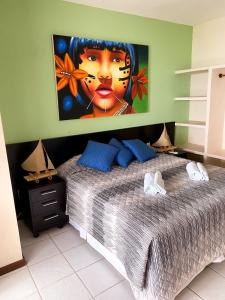 a bedroom with a large bed with a painting on the wall at Apartamentos Orrit Real Estate in Pipa