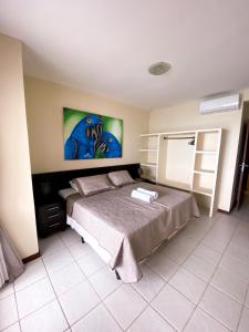 a bedroom with a bed with a painting on the wall at Apartamentos Orrit Real Estate in Pipa