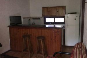 a kitchen with a white refrigerator and two bar stools at Casa ideal para pareja en Bella Vista - Maldonado in Bella Vista