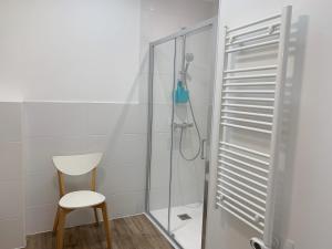 a shower with a chair and a glass shower door at Gîte Camdeborde 2 personnes au cœur du village de Laruns in Laruns