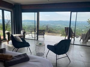 a bedroom with a bed and chairs and a large window at Rocky Road Mountain Lodge in Pretoria
