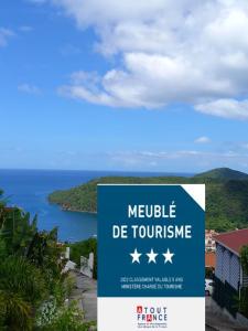 a sign that reads mobile de tourismence with the ocean in the background at Le DAMOUR Appartement 1 ou 2 chambres in Les Anses-dʼArlets