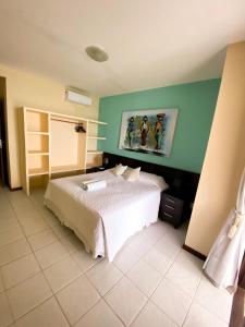 ein Schlafzimmer mit einem weißen Bett und einem Gemälde an der Wand in der Unterkunft Apartamentos Orrit Real Estate in Pipa