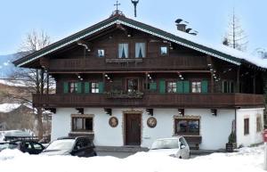 a large wooden house with cars parked in front of it at Appartement Seewaldhof in Brixen im Thale