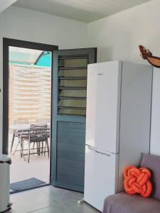 a kitchen with a refrigerator and a patio with a table at Le DAMOUR Appartement 1 ou 2 chambres in Les Anses-dʼArlets