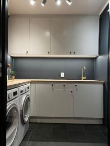 a kitchen with white cabinets and a washing machine at Nytt moderne hus på Storsteinnes in Storsteinnes