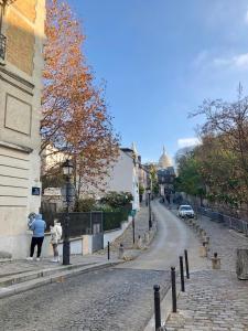 een vrouw en kind die over een geplaveide straat lopen bij Rare appartement d'architecte en haut de Montmartre in Parijs