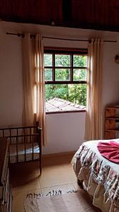 een slaapkamer met een bed en een raam bij Casa da Roça in Visconde De Maua