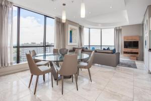 a dining room with a table and chairs and a couch at Luxury Penthouse at Sandton Skye in Johannesburg