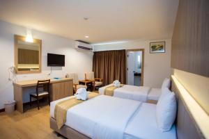 a hotel room with two beds and a desk at Sea Paradise Hotel Sattahip in Sattahip