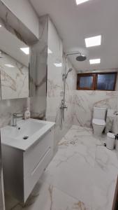 a white bathroom with a sink and a toilet at Guest House Gogemi in Bansko