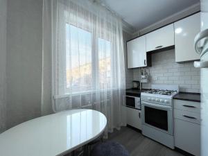 uma cozinha branca com uma mesa branca e uma janela em Двухкомнатная квартира, новый ремонт, 2 этаж, центр em Petropavl