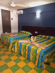 two beds in a room with people laying on them at Hotel Verasol in Veracruz