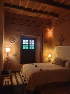 a bedroom with a bed with two lamps and a window at Maison d'hôtes IZZA in Kalaat MGouna