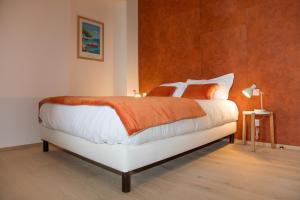 Schlafzimmer mit einem großen Bett mit orangefarbener und weißer Bettwäsche in der Unterkunft Villa Saint Enogat in Aix-les-Bains