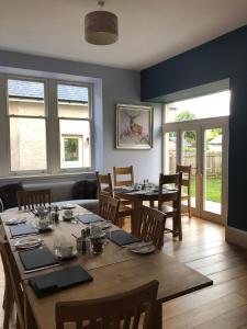 a dining room with a table and chairs and windows at Corsee House in Nairn