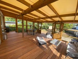 a large wooden deck with chairs and a table at Charmant Mobile-home 6 personnes sur terrain privé à 200 m de la plage - PADRIG in Ploemeur +5 photos